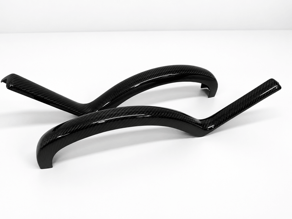 Two glossy black carbon fiber trunk arm covers with a carbon weave pattern, displayed on a clean white studio background.