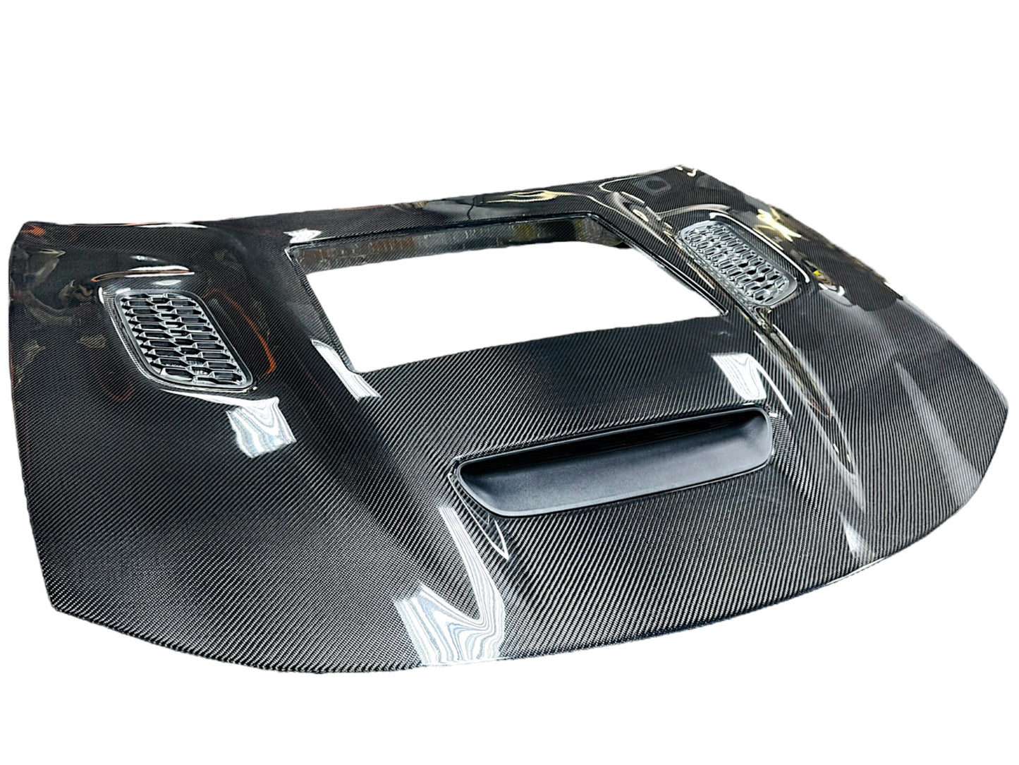 Carbon fiber hood for a Dodge Charger vehicle, featuring a glossy black finish and ventilation slots.
