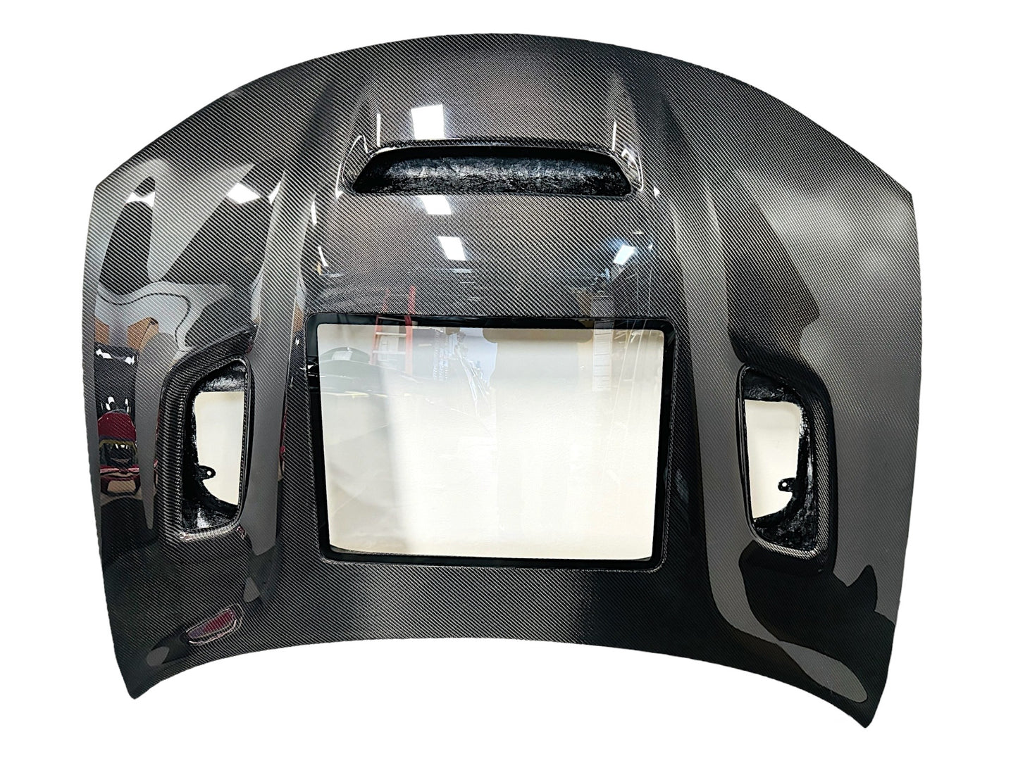 Carbon fiber hood for a Dodge Charger vehicle, featuring a glossy black finish and ventilation slots top view