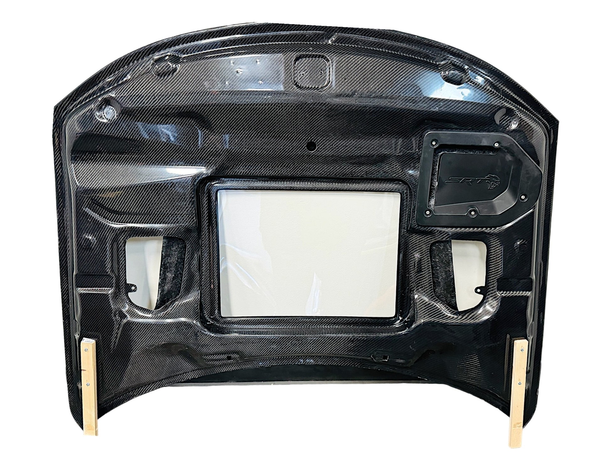 Carbon fiber hood for a Dodge Charger vehicle, featuring a glossy black finish and ventilation slots bottom view