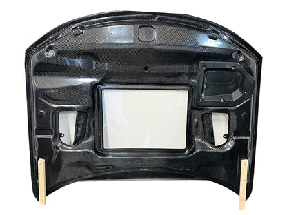 Carbon fiber hood for a Dodge Charger vehicle, featuring a glossy black finish and ventilation slots bottom view
