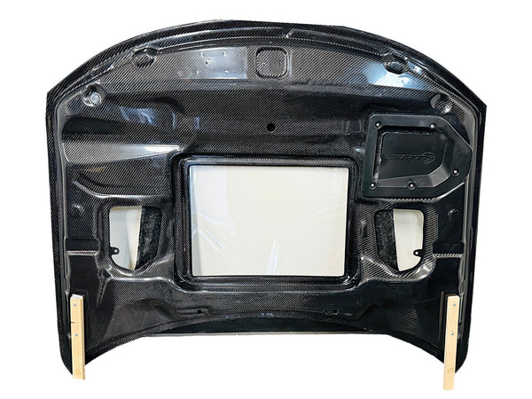 Carbon fiber hood for a Dodge Charger vehicle, featuring a glossy black finish and ventilation slots bottom view