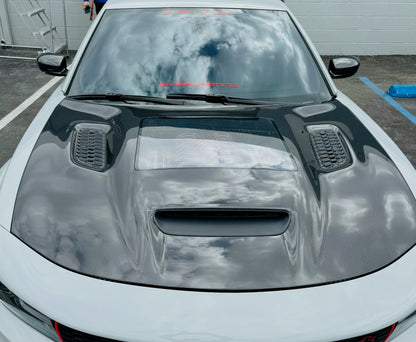 Installed Carbon fiber hood for a Dodge Charger vehicle, featuring a glossy black finish and ventilation slots