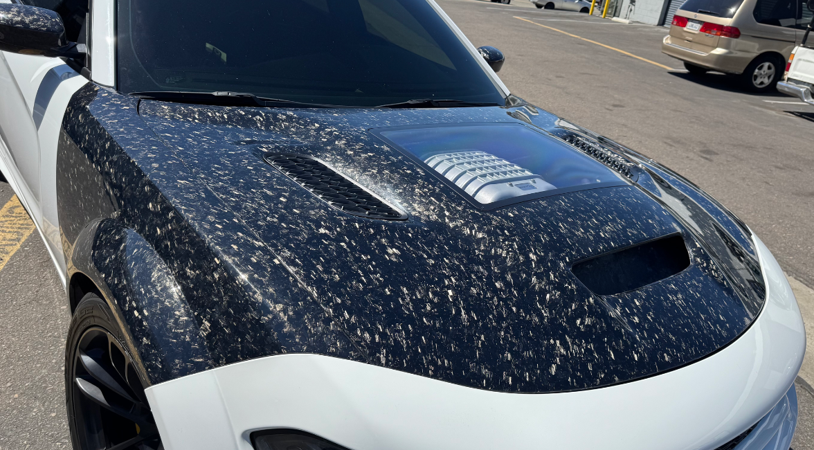 Installed Forged Carbon fiber hood for a Dodge Charger vehicle, featuring a glossy finish and ventilation slots