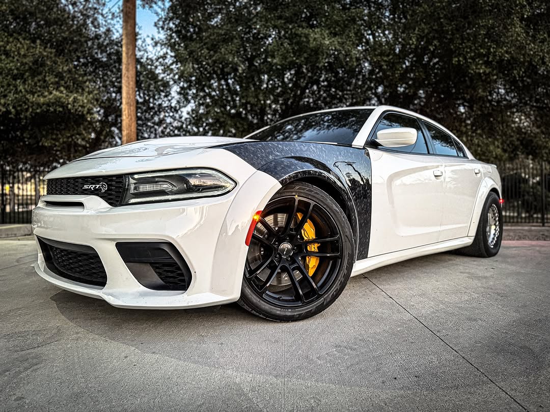 forged carbon fiber fenders on a Dodge Charger parked on a street with trees in the background