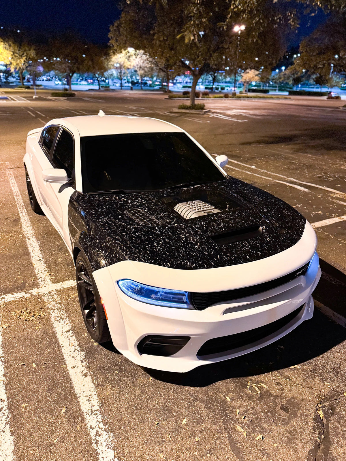 White car with forged carbon fiber fneders in a parking lot at night